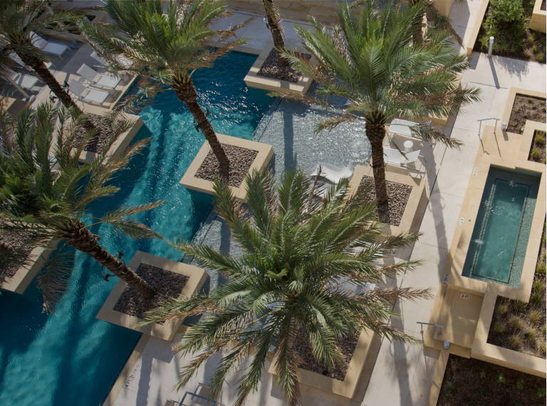Aerial view of a landscaped outdoor area featuring a pool, palm trees, and seating arrangements