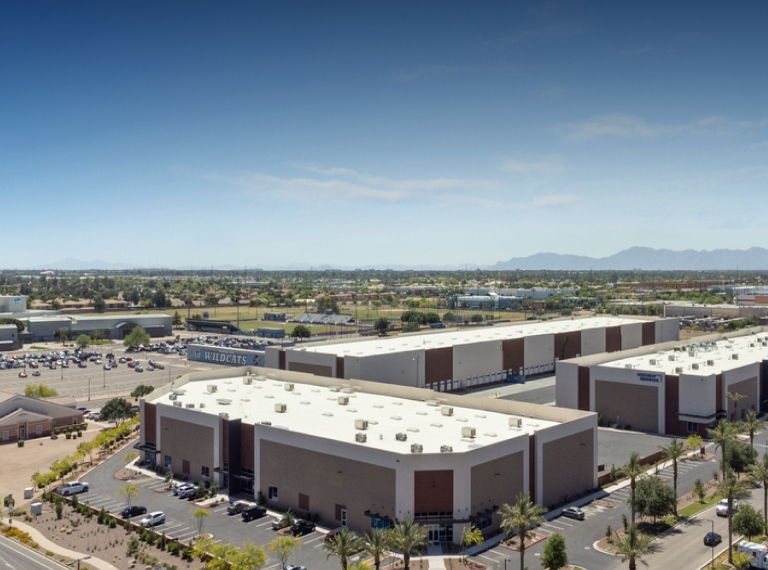 260 S McQueen, Pheonix, Arizona. An aerial view of rectangular buildings with a flat roofs. Many vehicles are parked around the building