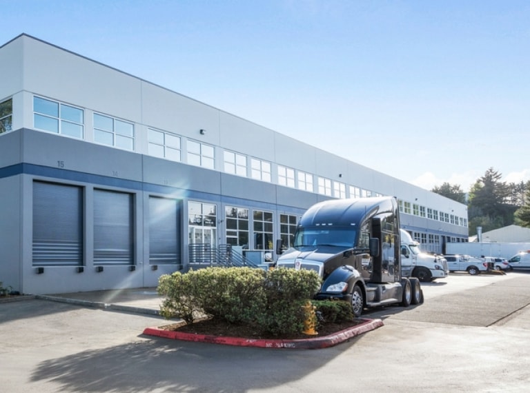 Vehicles parked outside a white, industrial building