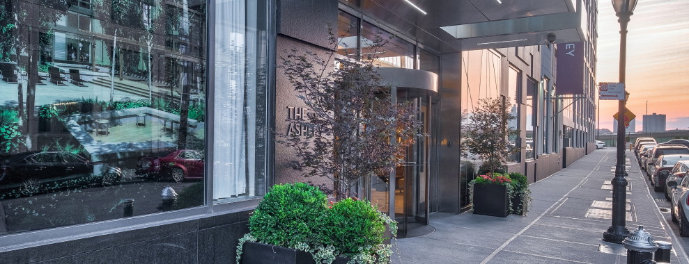 The front of a building with the number 400 displayed on the entrance. There is a revolving door with large glass panels and planters on the sides