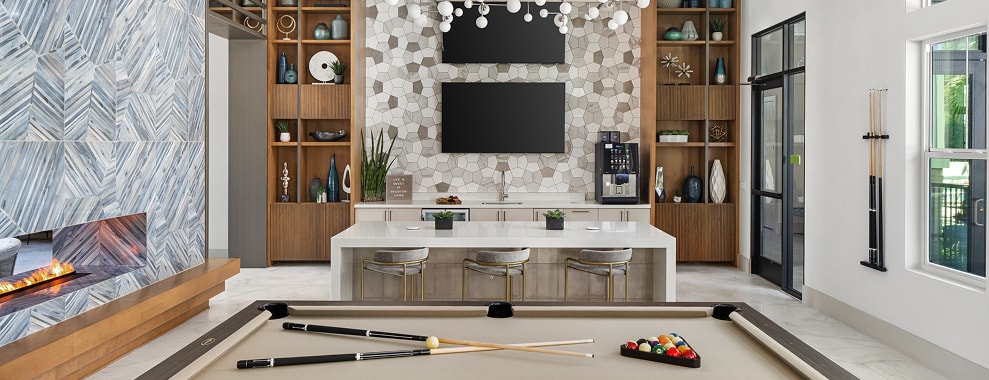 A modern interior space with shelving, a wall design, TVs, lighting fixtures, a counter top and snooker/pool table