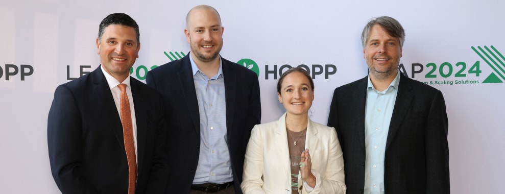 Four GID colleagues, one holding a trophy, in front of LEAP award branding