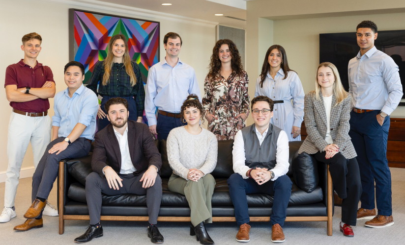 A group of individuals posing for a photo, some standing and some seated in an office space area