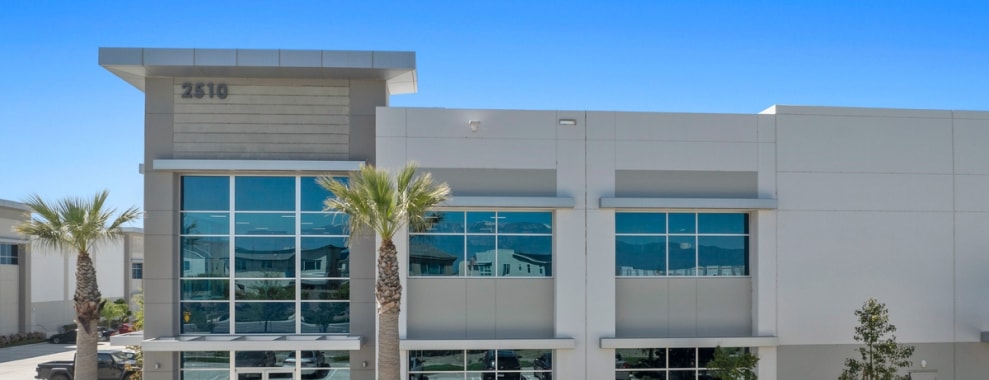 The exterior of an industrial, with palm trees either side of the entrance