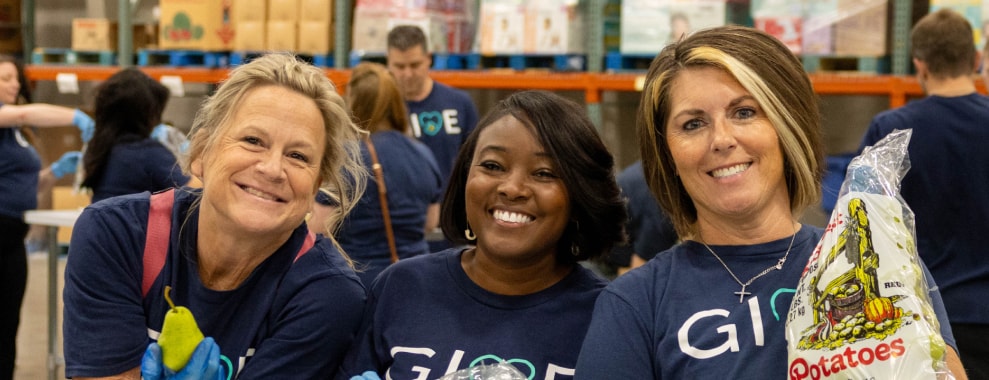 Three people all smiling at the camera wearing shirts with GIVE printed on them