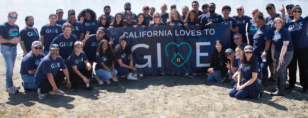 A large group of people holding up a banner that says California Loves To GIVE. Everyone is wearing matching shirts with the word GIVE printed on them