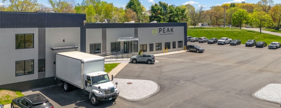 A building with the name PEAK on its facade. The building has multiple windows and a flat roof